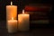 Three Pillar Candles Burning in a Dark Room with a Bible