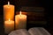 Three Pillar Candles Burning in a Dark Room with a Bible