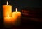 Three Pillar Candles Burning in a Dark Room with a Stack of Antique Books