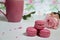 Three pink almond macaroons and mug with coffee on a white wooden background next to a pale pink rose. good morning