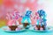 Three pink and blue novelty cupcakes decorated with candy and large lollipops.