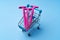 Three pink disposable shavers in shopping cart on blue background