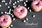 Three pink doughnut on a dark wooden background with marshmallows. Donuts with pink glaze closeup. No diet