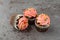 Three pink frosted chocolate cupcakes on a gray background side view