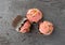 Three pink frosted chocolate cupcakes on a gray background top view