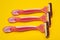 Three pink razors for women on a yellow background