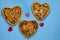 Three pizza in the form of a heart on a blue background with red hearts. Order pizza for a romantic dinner on Valentine`s Day