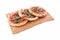 Three pizzas with ham, tomatoes, arugula on a wooden tray. The object is isolated on a white background
