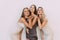 Three playful attractive young women standing and sending kisses isolated over white background