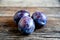 Three plums on old wooden boards.