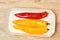 Three pods of sweet pepper lie in a cardboard tray on the table