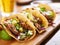 Three  pork carnitas street tacos in yellow corn tortilla with avocado, onion, cilantro and cabbage