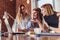 Three positive businesswomen working on laptop discussing joint business project