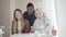 Three positive multiethnic colleagues talking in lunchroom, turning to camera and smiling. Portrait of happy smiling