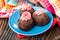 Three potato cakes with pink cream in blue saucer, napkin on table