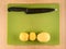 Three potatoes and knife on green plastic board