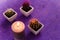 Three potted cactus plants with purple and orange thorns. Succulents and burning candles standing on purple background.