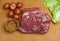 Three pound, raw, corn beef brisket, six small, red, potatoes and a leaf of cabbage, on a bamboo, wood, cutting board