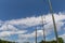 Three power poles, one covered in hardware cloth wire, against a beautiful blue sky with clouds