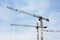 Three powerful construction cranes against the sky, while working. Construction