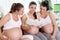 Three pregnant women reading a book,