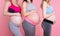 Three pregnant women touching baby bellies