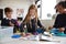 Three primary school children working together, following an instruction book and using construction blocks in a classroom, front