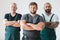 Three professional builder wearing overalls standing in empty interior