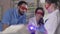 Three professional dental assistants using curing lights on mannequin. Middle Eastern man and Caucasian women in