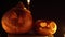 Three pumpkins with terrible grimaces in candlelight on a dark background