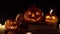 Three pumpkins with terrible grimaces in candlelight on a dark background