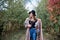 Three-quarter portrait of pretty blond woman walking in autumn park forest woods. Young girl, wearing black hat, blue mama jeans