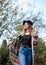 Three-quarter portrait of pretty blond woman walking in autumn park forest woods. Young girl, wearing black hat, blue mama jeans