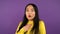 Three-quarter portrait of a young very surprised woman. Asian woman on purple isolated background. 4K
