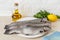 Three raw gutted trout fishes on a white plate over a kitchen table prepared for cooking. Fresh fish dishes, healthy eating and