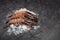 Three raw jumbo shrimps on ice on dark background.