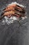 Three raw jumbo shrimps on ice on dark background with copy space. Vertical composition