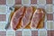 Three raw pork chops with spices and a hammer on a cutting board