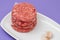 Three raw red meat burgers for hamburgers of minced ground beef on dish