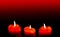 Three red burning candles with heart shaped decorations.