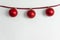 Three red Christmas ball hanging with rope on white cement wall holiday greeting background