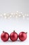 Three red christmas balls and some lights against white background.