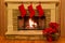 Three red Christmas stocking adorn an elegant stone fireplace for the holidays.