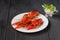 Three red crayfishes on white plate with sauce
