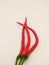 three red curly chilies in portrait mode on a white background.