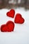 Three red hearts - candles on white snow, a gift for loved ones.