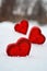 Three red hearts - candles on white snow, a gift for loved ones.