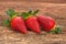 Three red ripe strawberries arranged on old rustic look timber