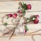 Three red roses, scattered flower petals, green leaves, glass round vase on wooden background top view closeup, floral arrangement