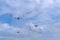 Three retro airplanes fly a triangle under white clouds in the blue sky